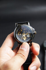 Black automatic self winding wristwatch with transparent sekeleton dial design on black leather background