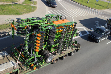 Transportation of new agricultural machinery by truck on a city street, on a highway, ring road.