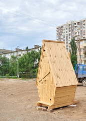 A wooden toilet stands in the middle of an ordinary city street