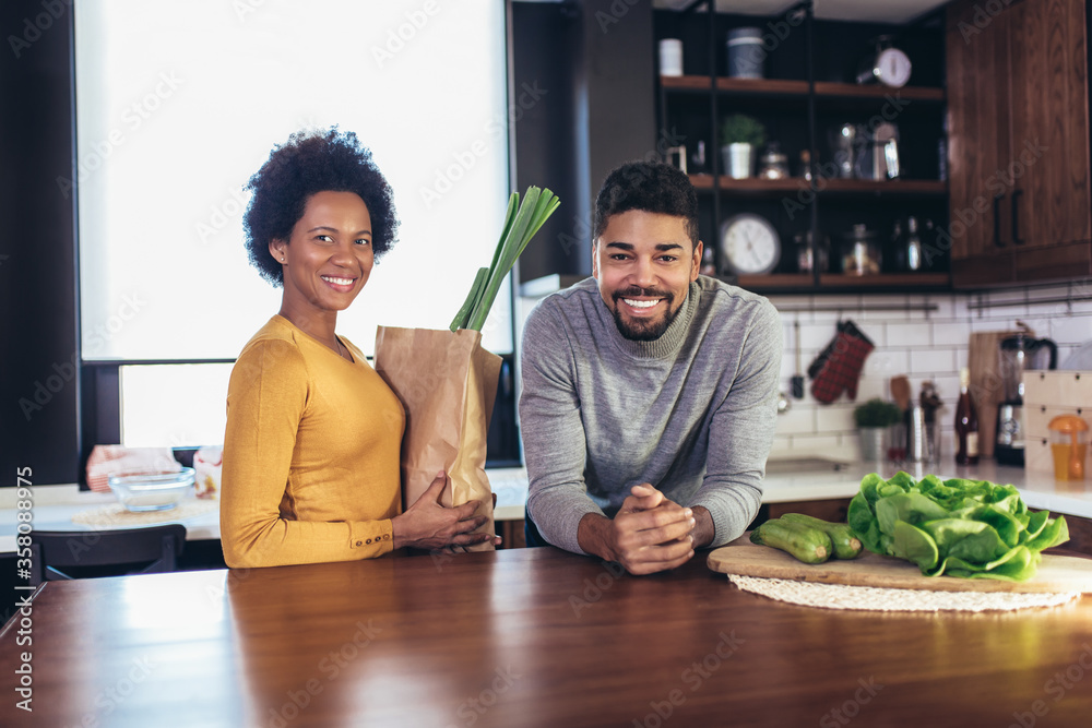 Wall mural happy african-american couple together in their kitchen at home