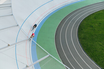 Two cyclists on cycle track outdoor. People racing at white velodrome.Cyclists athletes training on the bike path. Top view, background.Copy space