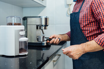 Man wearing plaid shirt and apron preparing an espresso