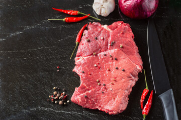 Raw beaf meat. Fresh steaks on slate board on black background. Top view