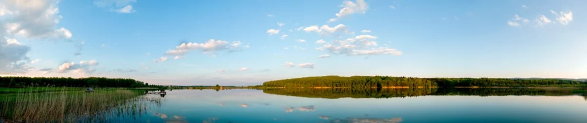 Foto op Canvas Panoramic landscape from the lake shore with colorful clouds in the spring sun. © mikhailgrytsiv