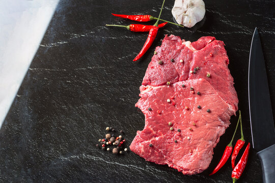 Raw beaf meat. Fresh steaks on slate board on black background. Top view