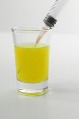 Syringe with yellow liquid on the white background. Syringe and glass on a white background. 