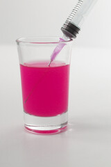 Syringe with pink liquid on the white background. Syringe and glass on a white background. 