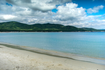 Fototapeta na wymiar Sea sand beach and turquoise sea on a background of green hills