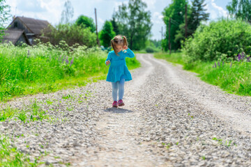 Fototapeta na wymiar Little girl walks on a dirt road in the village