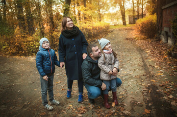 Parents and children walk in the autumn park, they saw something upstairs and look there. Soft focus
