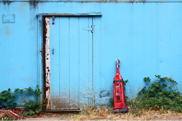 Old  red vacuum stand near a abandoned blue wooden barn in the country