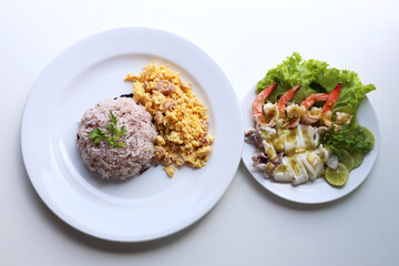 Riceberry with omelette With steamed lemon seafood served in a white round dish Put on the white table Ready to eat