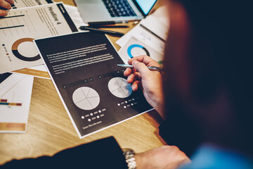 Faceless entrepreneur browsing report in office