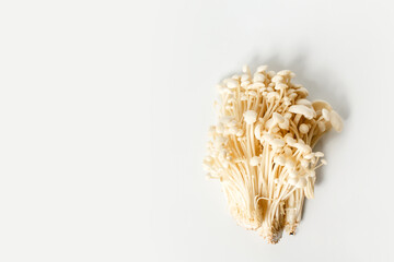 Heap of little white enoki mushrooms on neutral white background, close-up