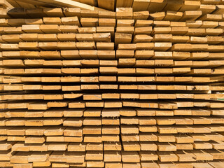 A large pile of boards sawn from trees on a sawmill for the procurement of building materials for construction. Construction industry.