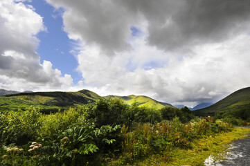 Obraz premium Magnifique vue panoramique sur les monts et les collines dans un val à l'embouchure d'un bras de mer en Irlande. Ciel orageux, verdure et clair-obscur.