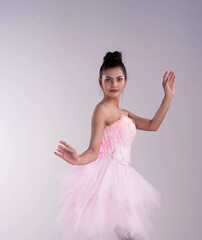 Young beautiful lay wearing pink ballet suit,raise hands up in the air,model posing on background