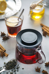 Hot bright tea in a glass teapot on a stone gray background, selective focus with a small depth of field, fragrant tea with spices lemon and honey