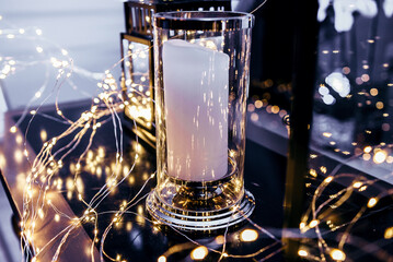 Big white candle in a glass flask. New Year's decoration.