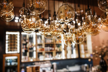 Round light bulbs in the foreground. Bar counter with alcohol in the background in blur. Glass bottles on the shelves.