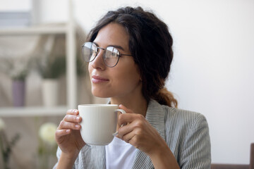 Close up of pensive young Caucasian woman in glasses drink coffee look in window distance thinking pondering, thoughtful millennial female in spectacles lost in thoughts dreaming or visualizing