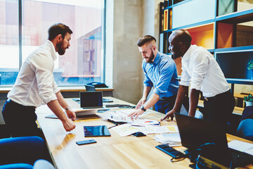 Fototapeta premium Businessmen in shirts discussing strategy and collaborative process of during brainstorming meeting around table in office interior.Diverse employees working in team on managing and marketing solution