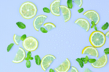 Juicy lemon slices and mint leaves on blue table top view. Flat lay style.