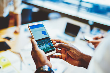 Cropped view of man's hands downloading application on digital smartphone device.Selective focus online chat in social networks on modern telephone device using 4G internet