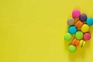 Obraz premium Sweet almond colorful unicorn pink blue yellow green macaron or macaroon dessert cake isolated on trendy yellow modern fashion background. French sweet cookie. Minimal food bakery concept. Copy space