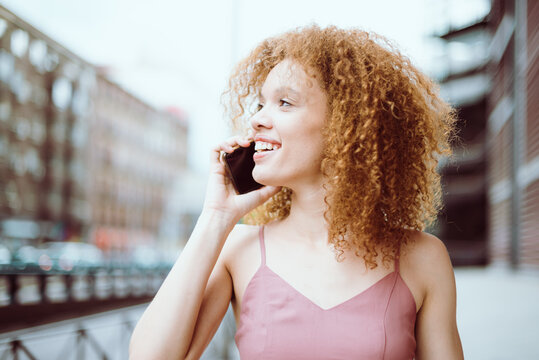 Primer plano de una hermosa modelo joven   hablando por teléfono celular en plena calle. Retrato cercano de una bella chica brasileña con un gesto cotidiano como hablar por teléfono en plena calle. 