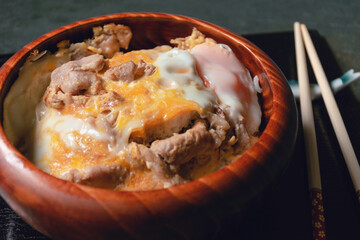 Baked Pork Rice with Eggs in a Wooden Bowl, Kitchen Tableware, Top View Green Wood Background with Natural Light by Morning Window, Japanese style food, Selective focus.