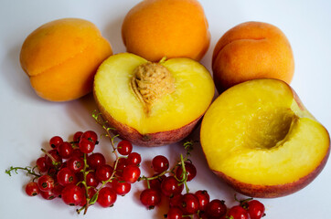 sprig of red currant with peach halves on a white background