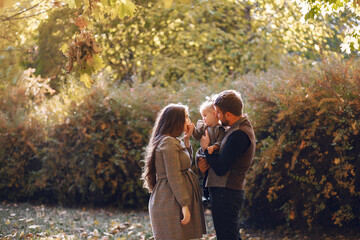 Fototapeta premium Family in a autumn park. Woman in a brown dress. Cute little girl with parents