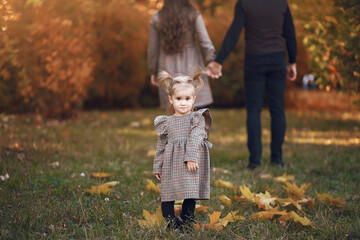 Family in a autumn park. Woman in a brown dress. Cute little girl with parents