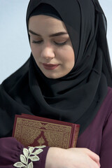 a young beautiful Muslim woman with hijab in the holy month of Ramadan embraces and learns the Qur'an