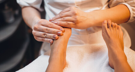 Caucasian woman having a massage for her legs and fingers lying on the couch in a spa center
