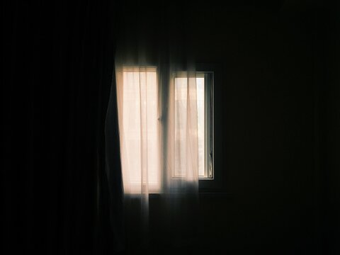 Window with curtains in a dark room during daytime