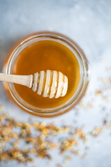 Honey and honey spoon on a light background. Sweet honey in the jar, place for text.
