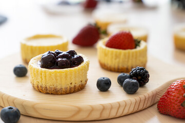 Mini cheesecake with blueberry, blackberry and strawberry ready to be served on wooden table