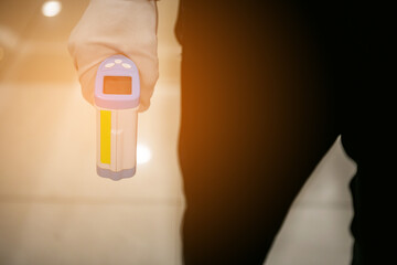 Close-up shot of digital thermometer Gun with sunlight background, Non-Contact Infrared Sight Handheld Forehead Readings from Coronavirus Disease 2019 (COVID-19)  Epidemic virus outbreak concept
