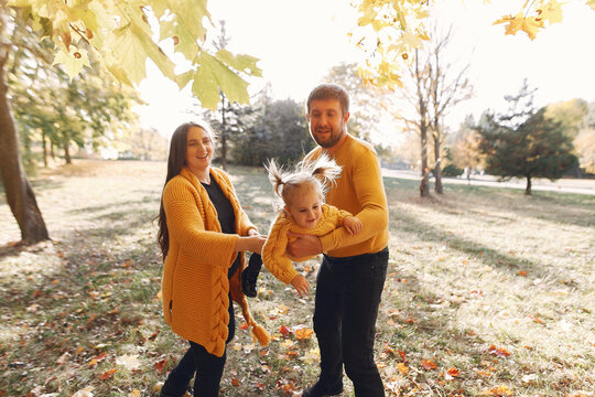 Family In A Autumn Park. Woman In A Yellow Sweater. Cute Little Girl With Parents