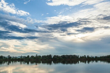 The sky and the forest are reflected in the river.