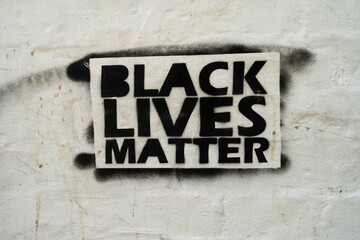 A Black Lives Matter sign which has been spray painted with a stencil on a white brick wall in Soho, Central Lonodn