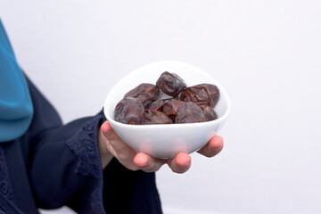 portrait of a beautiful Muslim woman with a hijab on a black background holds dates in her hands in the holy month of Ramadan.