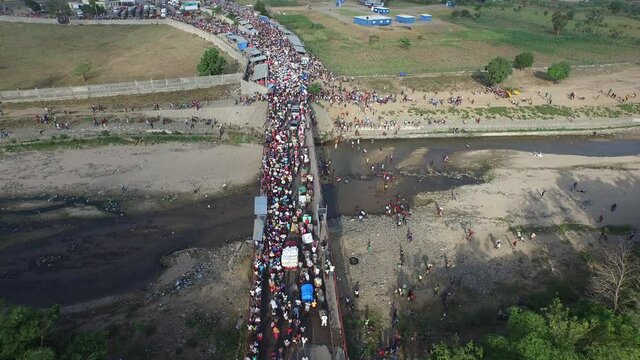 Dajabon bridge with crowd crossing border in Dominican Republic. Aerial rising