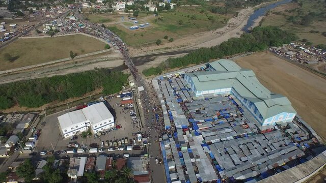 Aerial orbit at Dajabon market and crowd crossing river, Dominican Republic