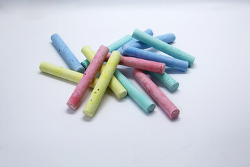 Colored chalk, in the form of small elongated cylinders in a wide variety of colors, used as school supplies for writing or drawing on a blackboard.