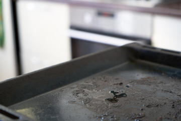 Dirty baking sheet.  Dirty oven pan on a kitchen background