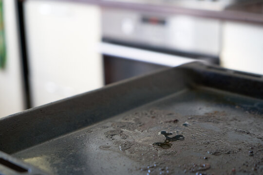 Dirty baking sheet.  Dirty oven pan on a kitchen background