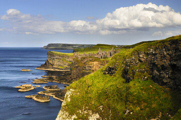 Vue panoramique sur les falaises verdoyantes et les ruines du ch&acirc;teau de Dunluce sur la c&ocirc;te nord irlandaise.
